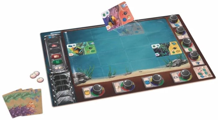 A game board that looks like an aquarium. Surrounding it are game cards, pieces, and dials.