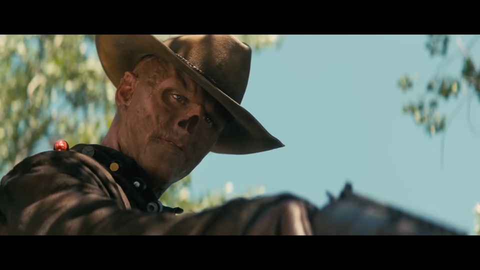 A ghoul looking down and to the right, pointing a gun at something.