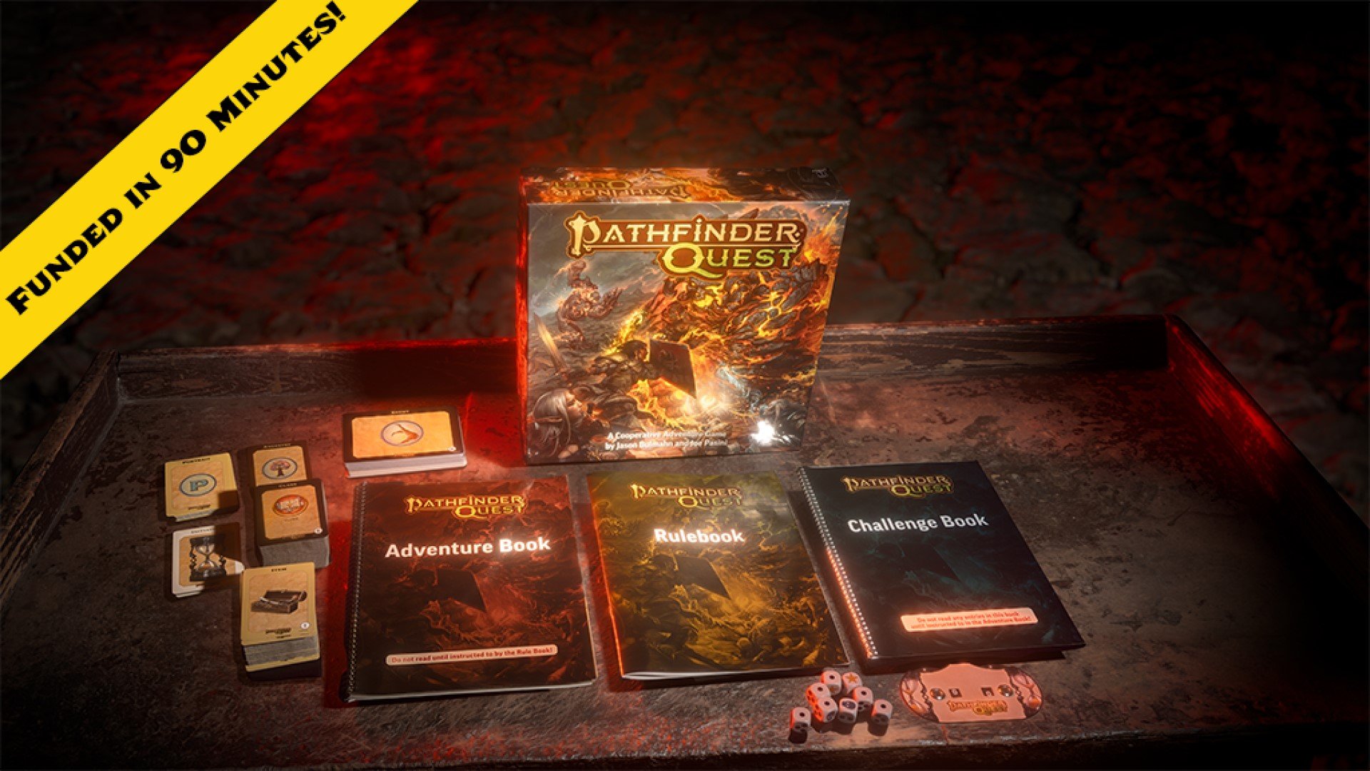 The game box of Pathfinder Quest, several softcover books, and decks of cards on a wooden desk. A chyron stating, "Funded in 90 Minutes" is visible on the upper left corner.
