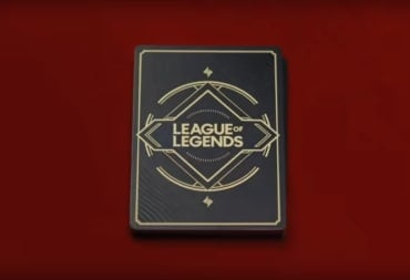 A deck of cards on a red mat with the title League of Legends written on them in brass letters.