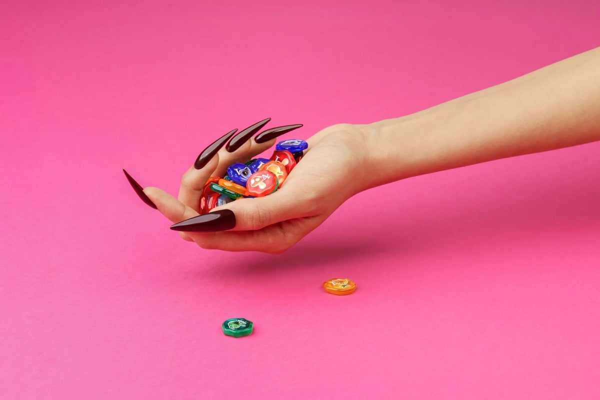 An image from our Quacks board game review featuring a hand holding a bunch of tokens