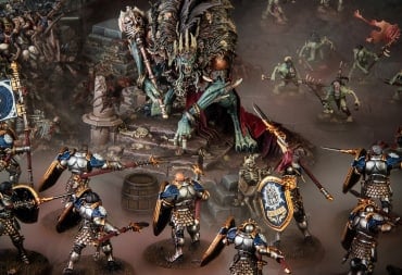 A collection of miniatures, one of a giant undead wearing a crown surrounded by knights in armor, on a blasted battlefield.